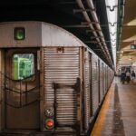 A subway train parked at an urban subway station platform with passengers walking by.