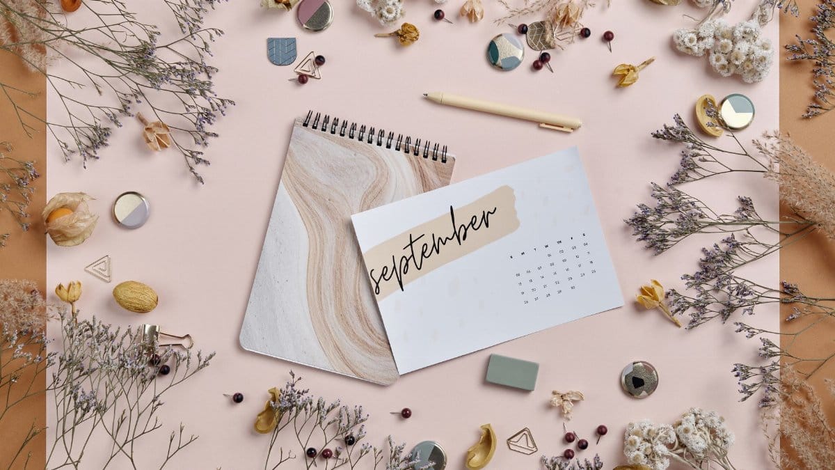 Artistic flatlay featuring a September calendar, dried flowers, and stationery elements.