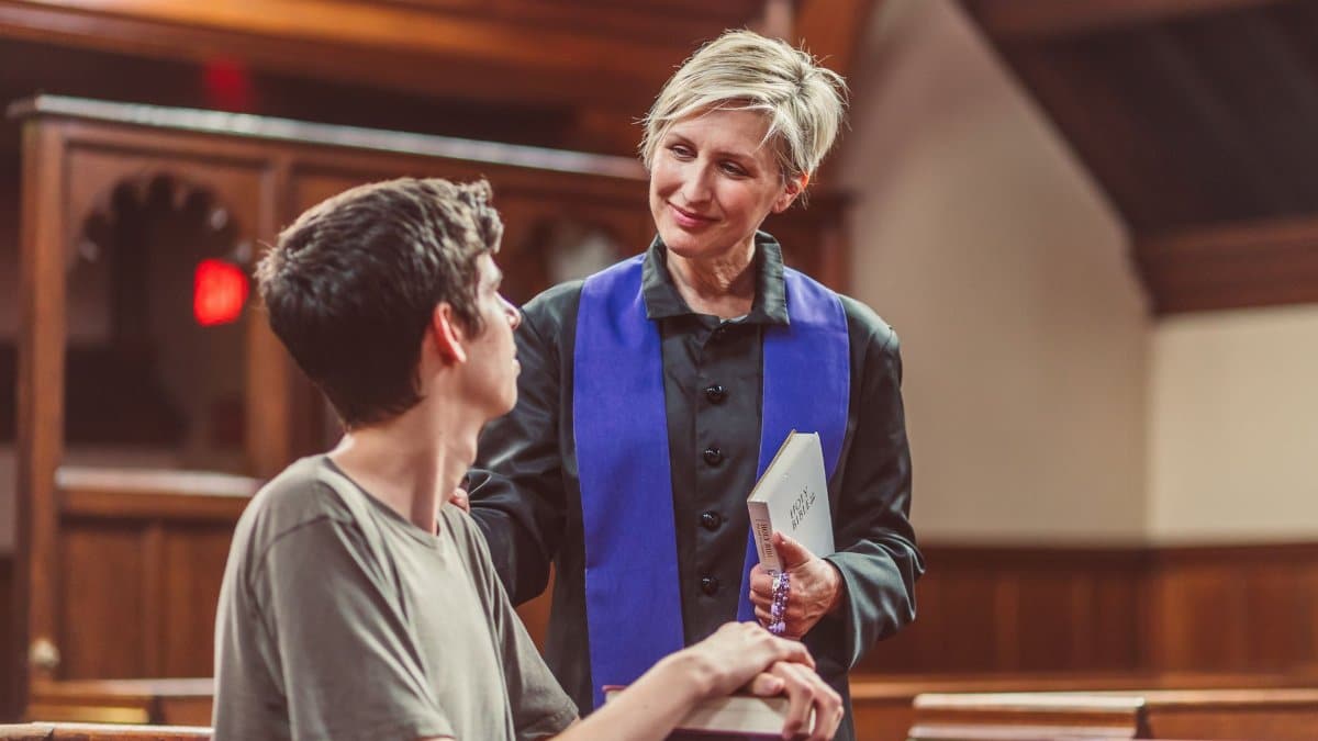 A clergy member and a young man in a warm conversation inside a church.