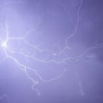 Dramatic lightning bolt captured in a striking purple night sky.