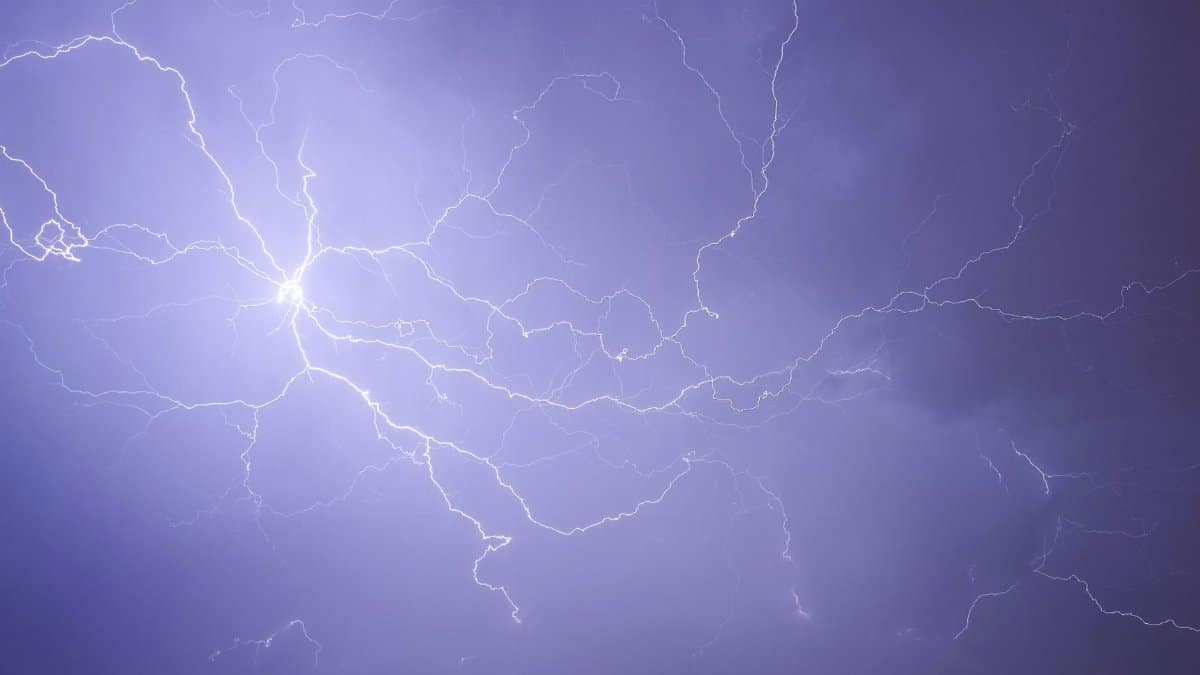Dramatic lightning bolt captured in a striking purple night sky.