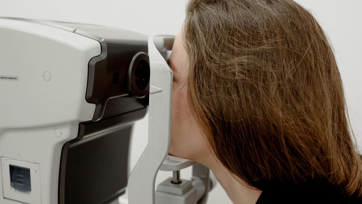 Side view of female client checking vision during medical treatment in ophthalmology clinic