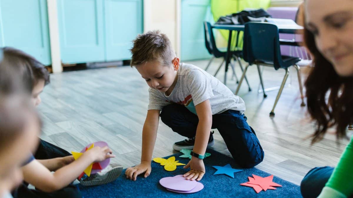 Children playing with colorful shapes in a classroom setting, fostering creativity and learning.
