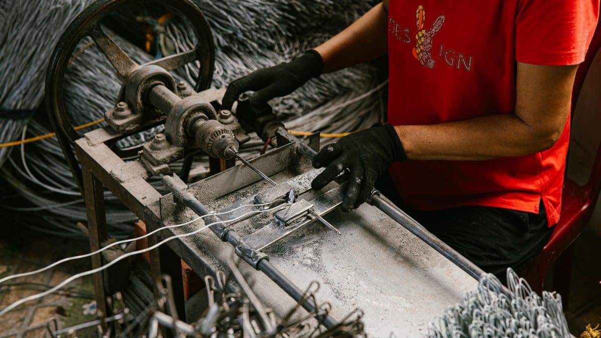 A person in a workshop uses a wire bending machine, highlighting craftsmanship and industry.