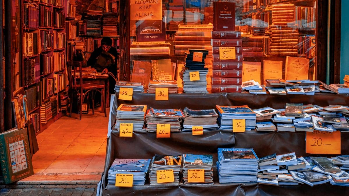 Warmly lit bookstore featuring an eclectic mix of vintage books with price tags in a quaint setting.