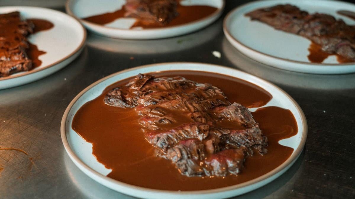 Deliciously cooked sliced picanha served with rich barbecue sauce on white plates, perfect for gourmet dining.