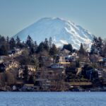 Scenic view of Mount Rainier with residential suburb along the water on a clear day.