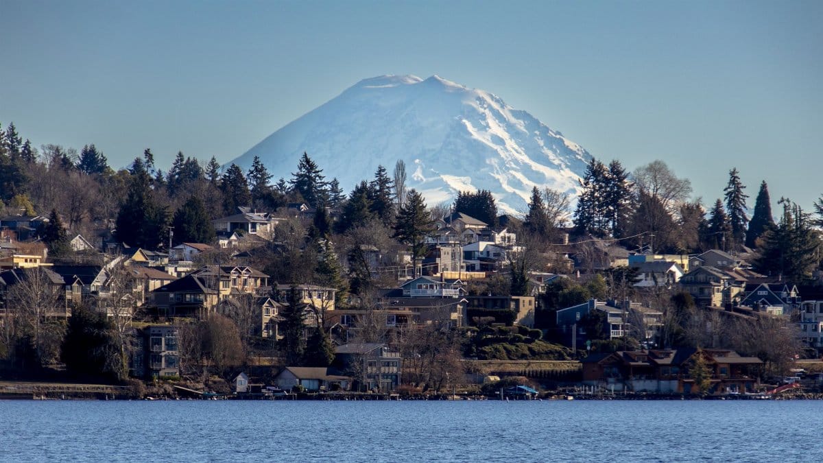Scenic view of Mount Rainier with residential suburb along the water on a clear day.