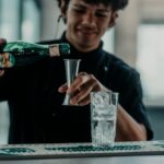 A bartender skillfully pouring Fernet into a glass in a modern Buenos Aires bar setting.