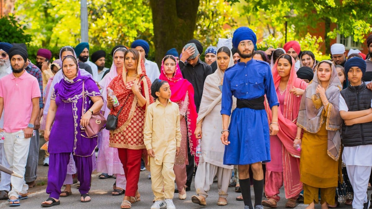 A diverse group participates in a cultural parade, showcasing vibrant traditional attire and community spirit.