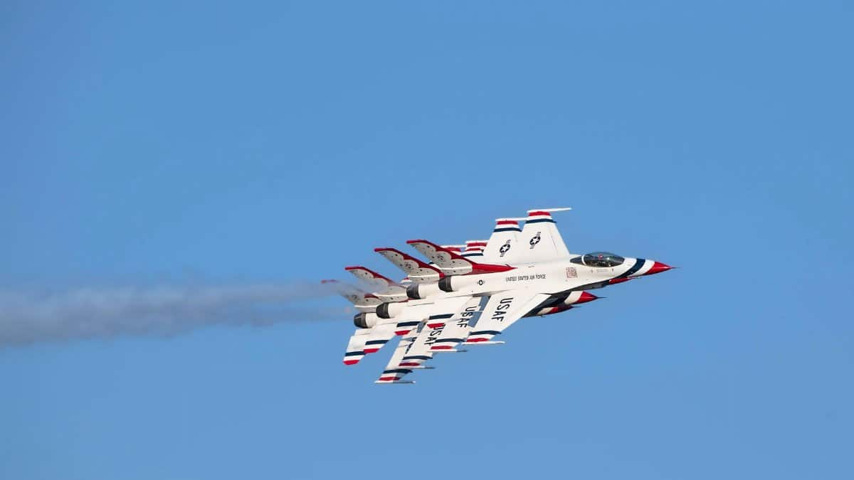 USAF Thunderbirds in precision aerobatic formation against a clear blue sky.