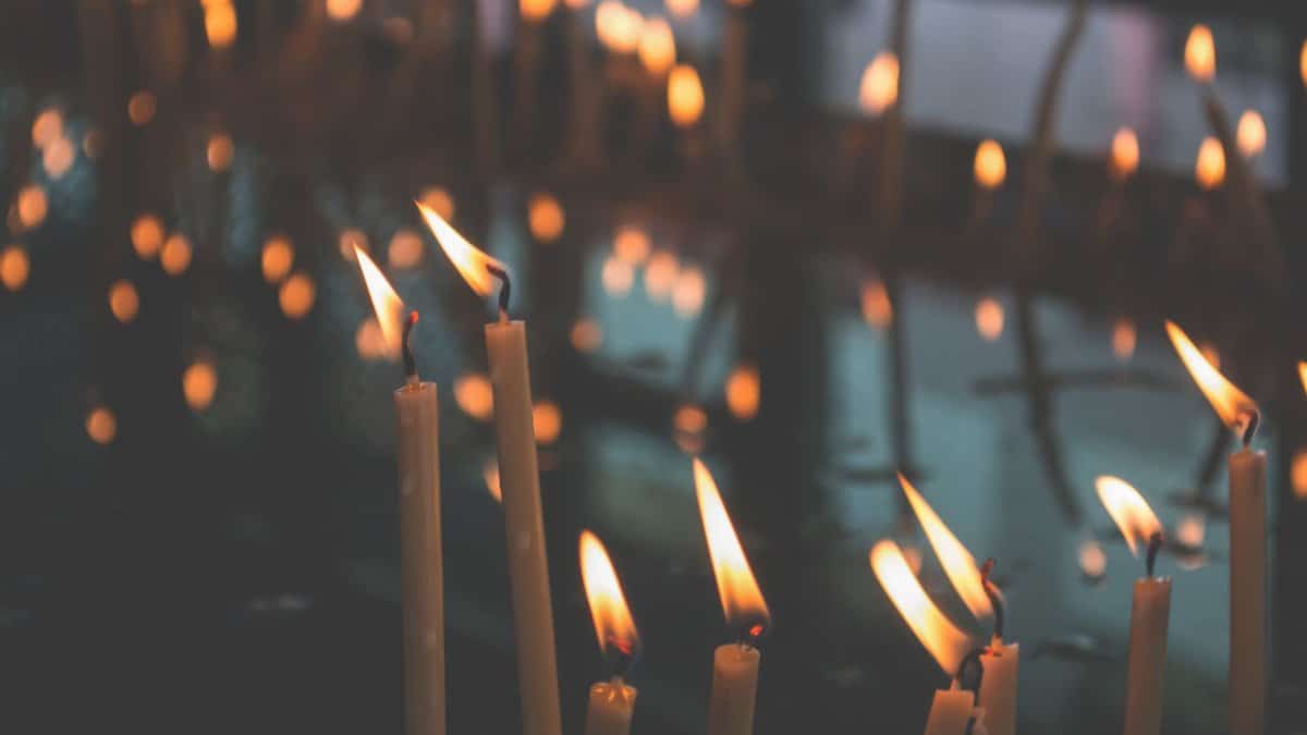 A tranquil scene of burning candles casting warm light in a dark interior, ideal for spiritual or meditation themes.