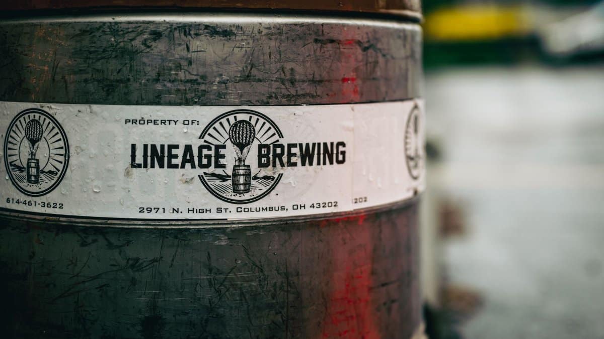 Close-up photo of a Lineage Brewing barrel with label details. Captured outdoors, offers an industrial feel.