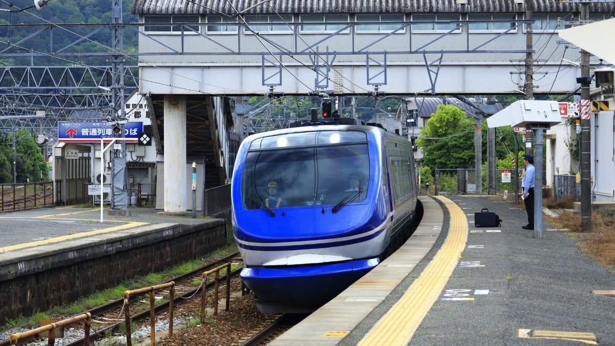 A sleek blue express train arrives at Kamigori Station, Hyogo, Japan with visible platform and footbridge.