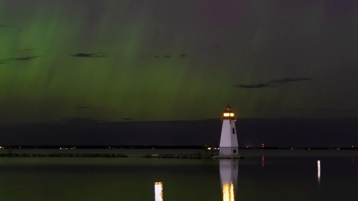 Stunning view of the aurora borealis illuminating the night sky over a lighthouse in Georgina, Ontario.