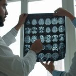 Two doctors examining MRI brain scans in a well-lit hospital room.