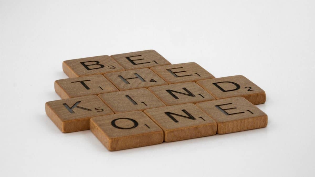 Wooden Scrabble tiles arranged to spell 'Be the Kind One', promoting kindness.