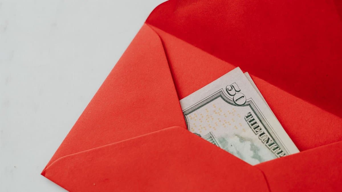 Close-up of fifty dollar bill in a vibrant red envelope, ideal for gift or money exchange stock photo.