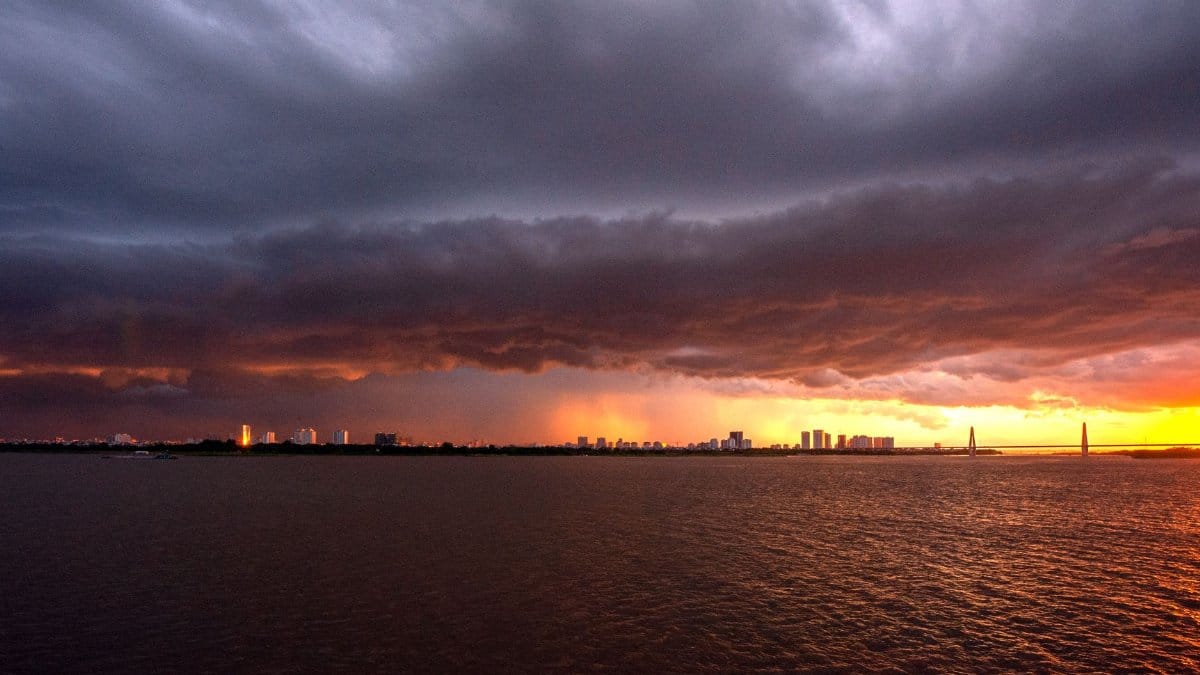 A city skyline under a dramatic stormy sky with a vibrant sunset provides a powerful contrast.