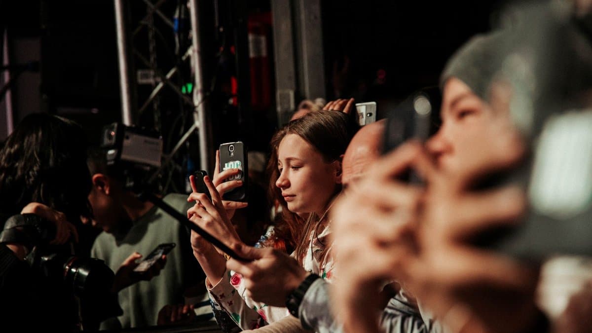 People eagerly capturing a live event on their smartphones, showcasing audience engagement.