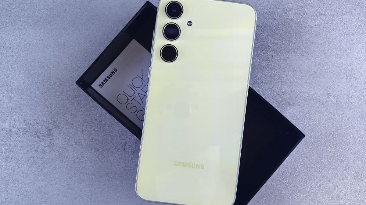 Yellow Samsung smartphone displayed on a gray surface with its box and quick start guide.
