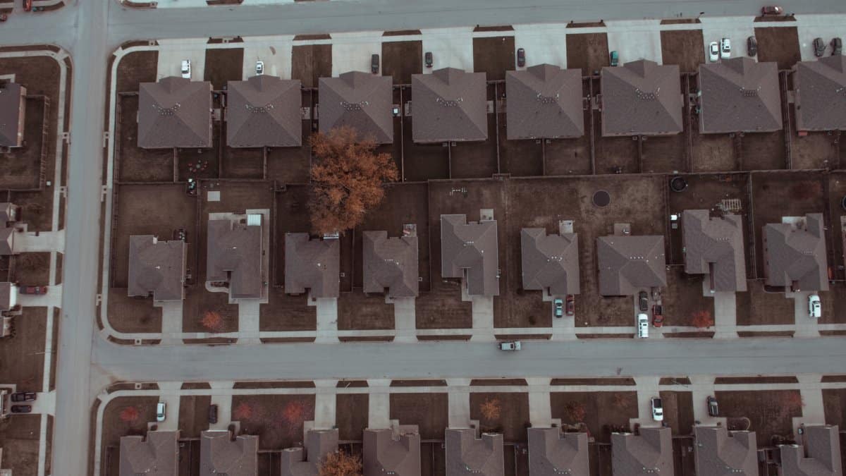 Top view image of a suburban neighborhood with houses, roads, and driveways.