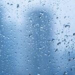 Raindrops on a window with blurred cityscape background creating a tranquil mood.