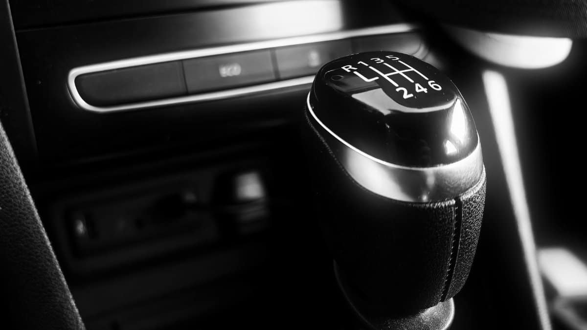 Black and white close-up of a manual gear shift in a modern car interior, highlighting sleek design.
