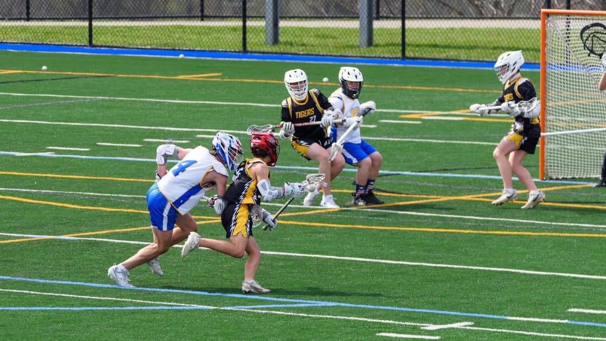 Action-packed lacrosse game in progress on a sunny day with players in team uniforms competing passionately.