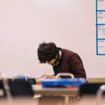 A high school student studying and solving problems in a classroom setting.