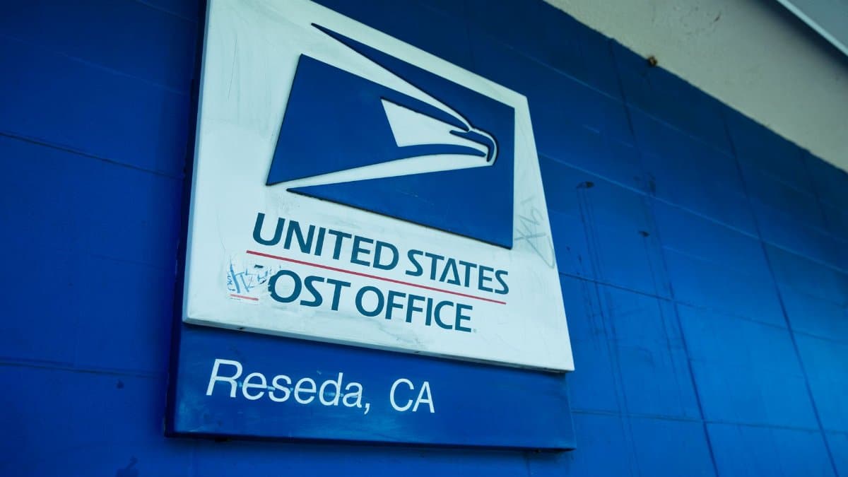 Close-up of the United States Post Office sign against a blue wall in Reseda, CA.