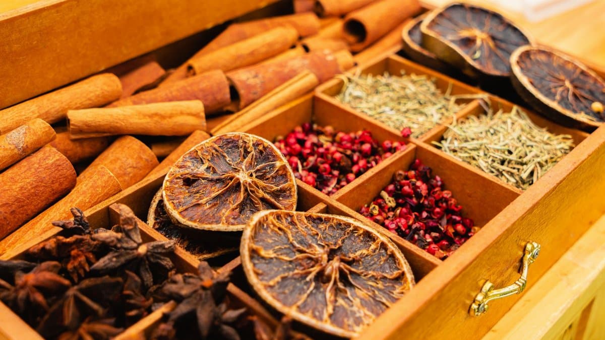 A wooden box filled with assorted spices and dried citrus slices, showcasing natural flavors.