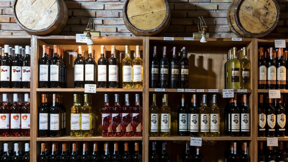 A rustic wine cellar showcasing a variety of wine bottles against a brick wall and wooden barrels.