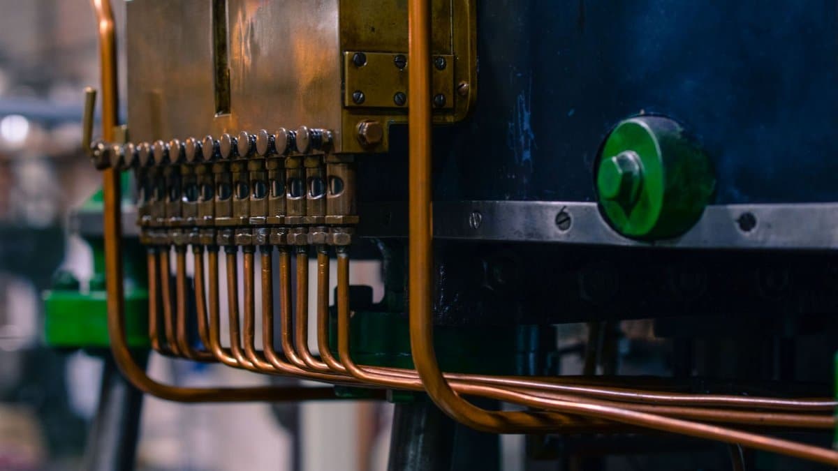 Detailed view of industrial machinery featuring copper tubing and steel components in a factory setting.