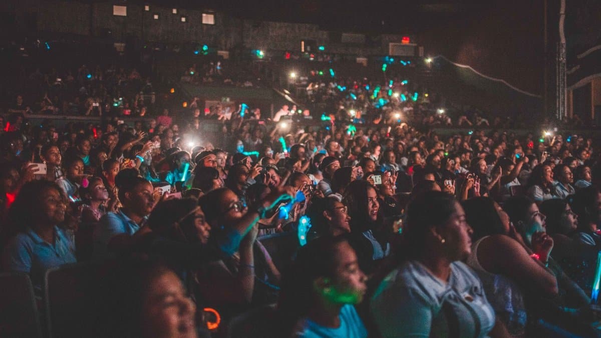 A vibrant audience enjoying a live music concert with colorful lights in a large venue.