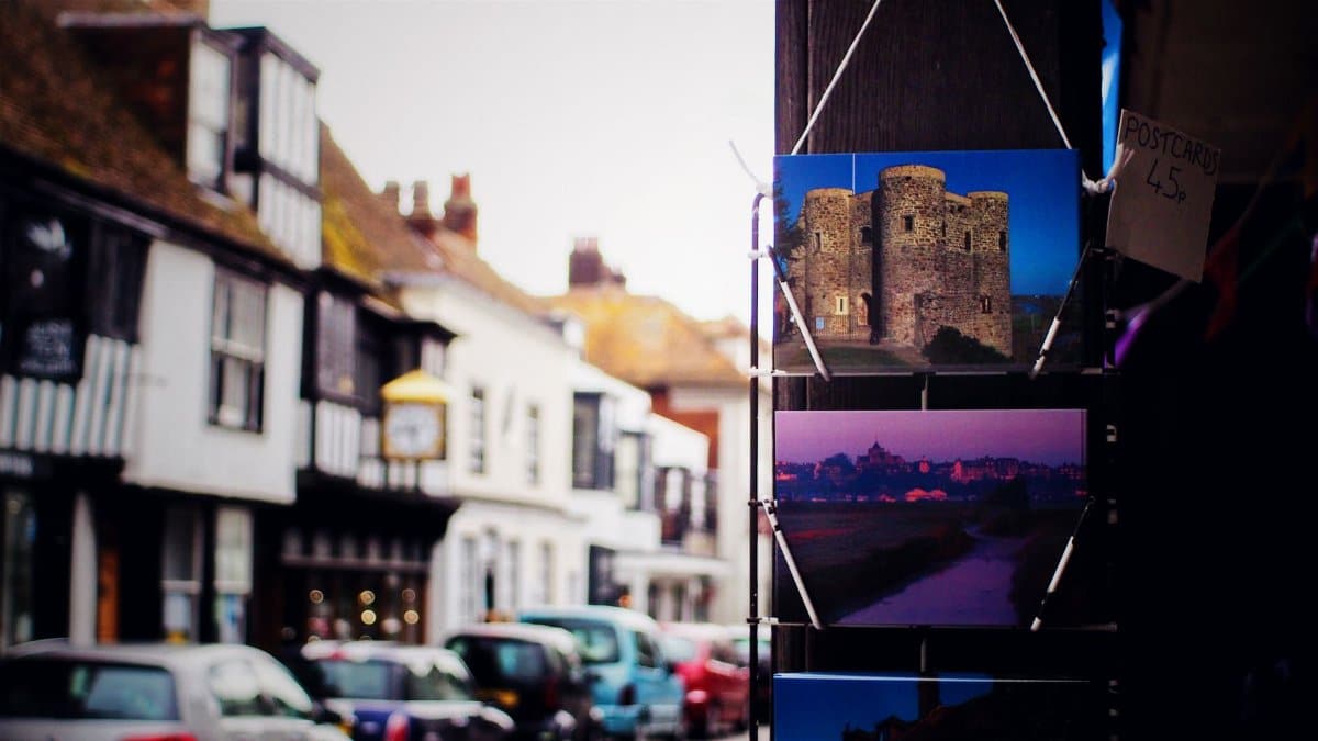 A picturesque British street with vintage houses and a vibrant postcard display.