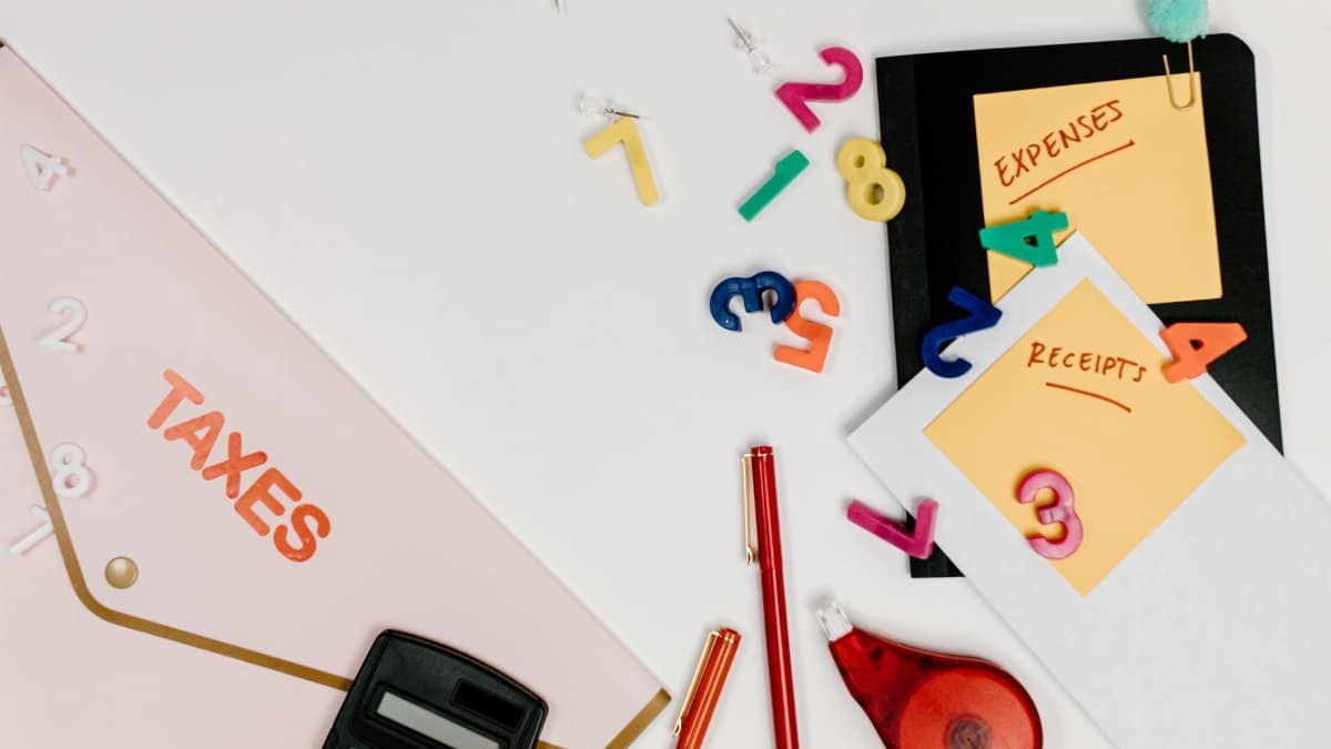 Flat lay of tax documents, receipts, calculator, and colorful numbers for budgeting.