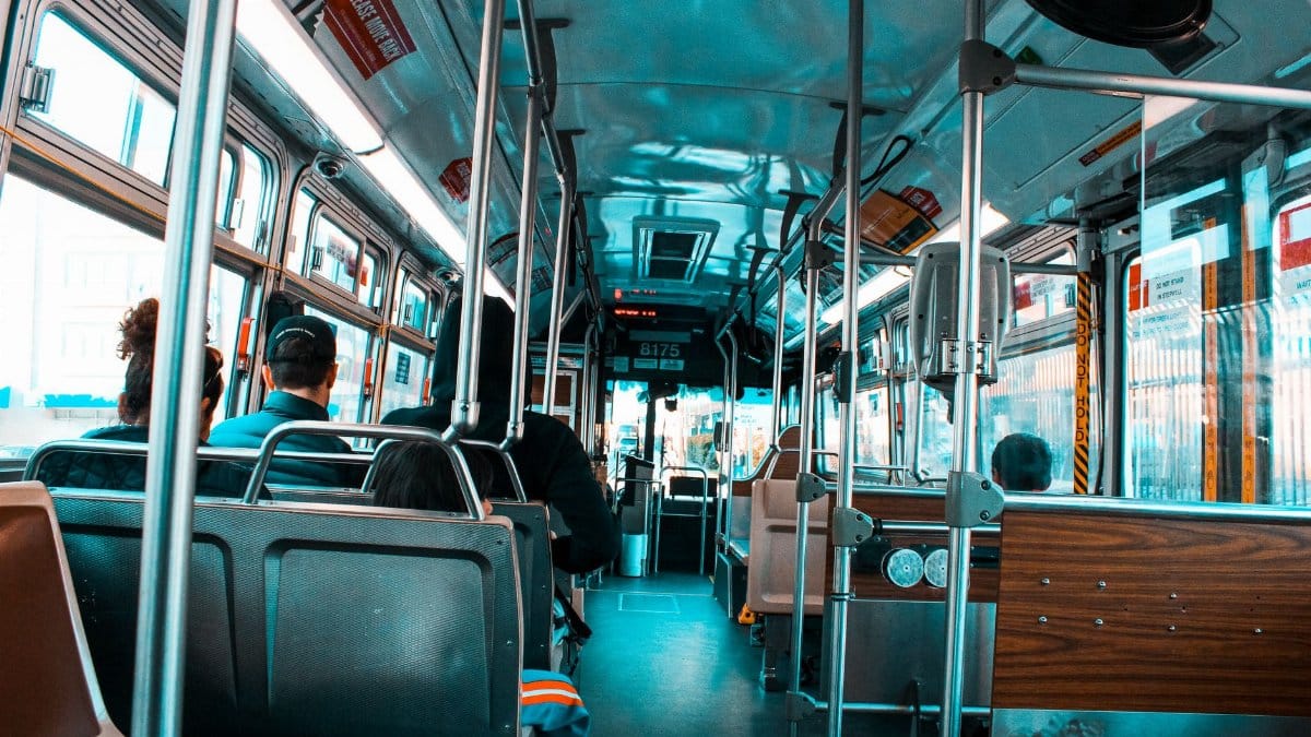 Interior shot of a city bus filled with diverse passengers commuting during the day.