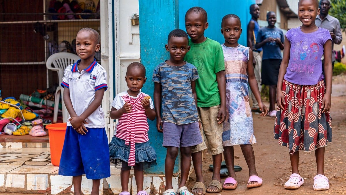 A heartwarming scene of smiling children standing outdoors in bright outfits, showcasing joy and diversity.