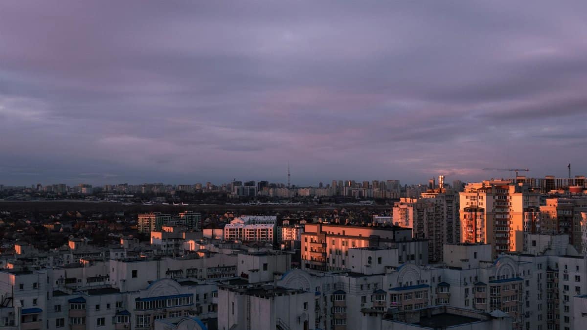 Aerial view of Kyiv city with striking clouds and sunset light over the urban skyline.