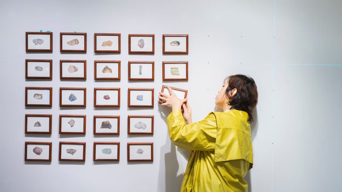 A curator arranging framed art in a modern exhibition in Tokyo, Japan.