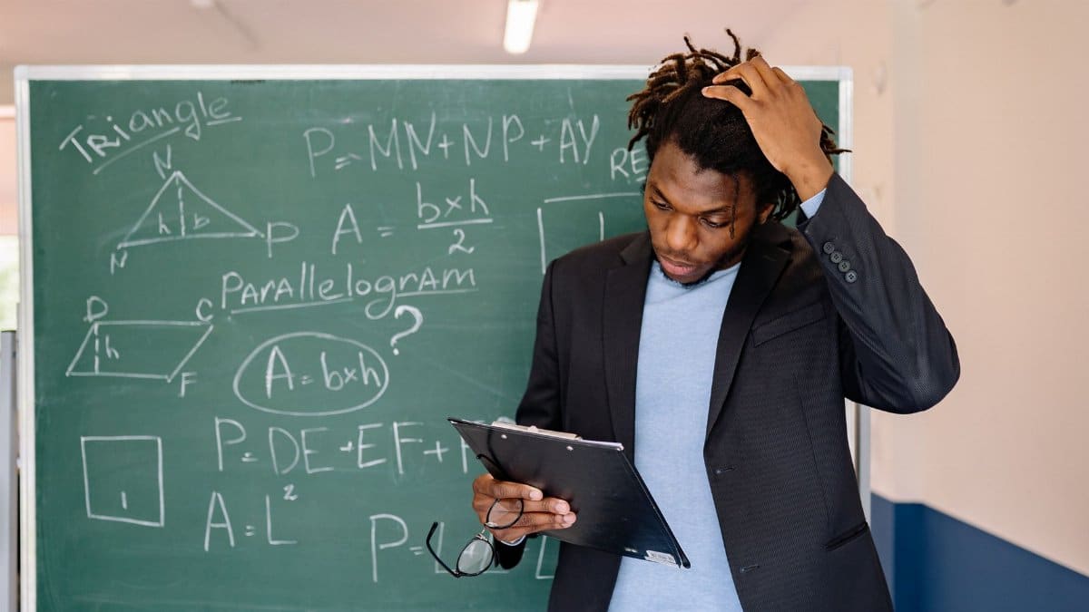 A teacher in a classroom solving math problems on a chalkboard, illustrating education and learning.