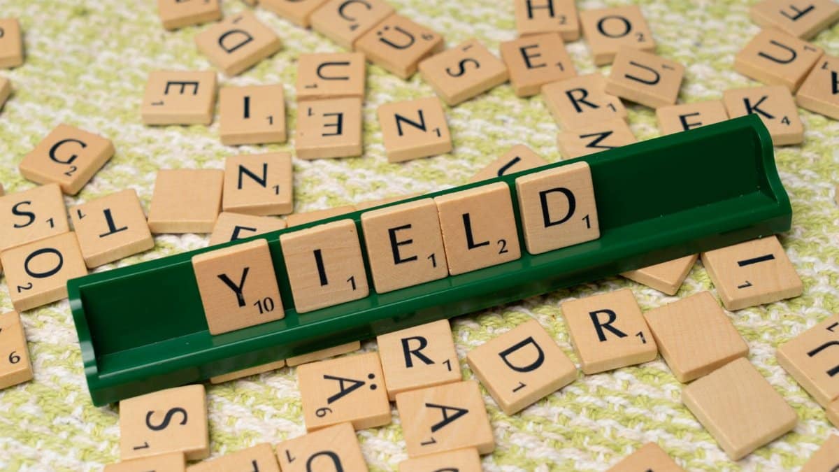 Scrabble tiles spelling 'Yield' on a rack among scattered letters.