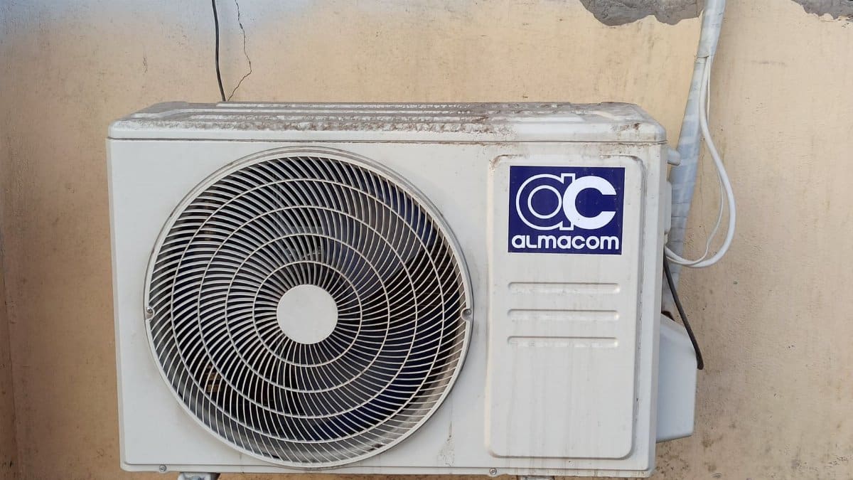 A well-used outdoor air conditioning unit affixed to a brick wall, showcasing urban climate control.