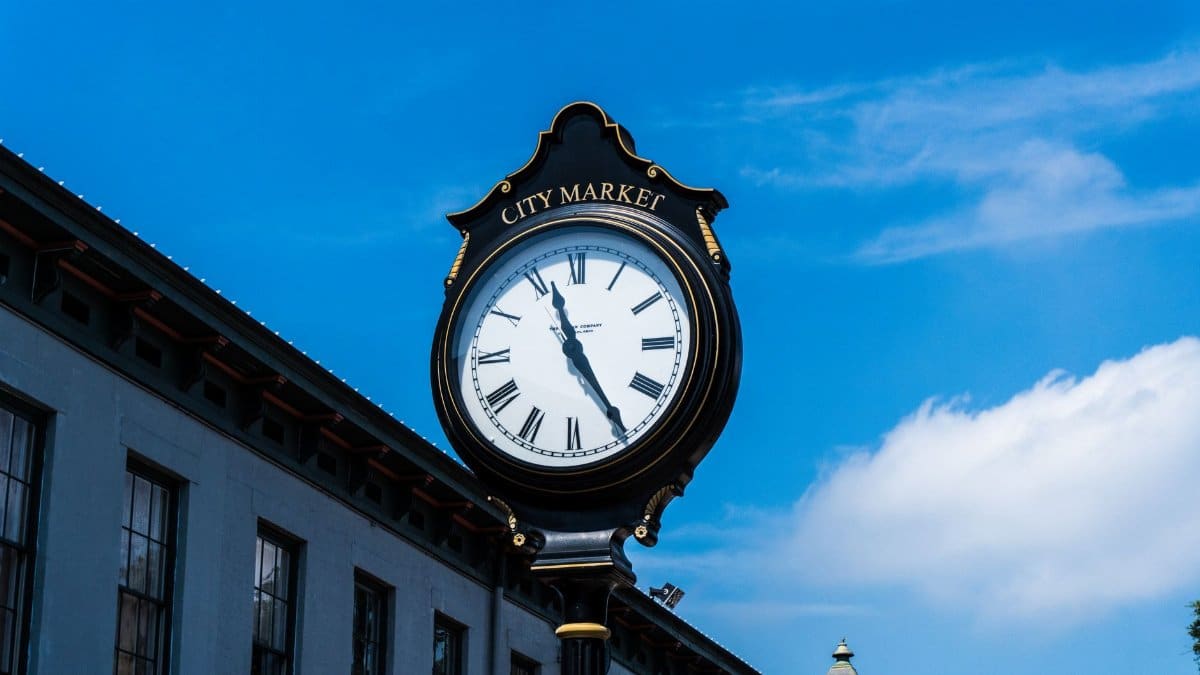 Elegant post clock at City Market with clear blue sky backdrop, showcasing urban architecture.