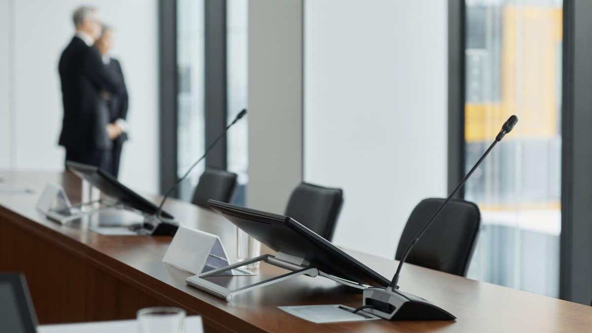 Sleek conference room setup with microphones, digital displays, and modern design elements.