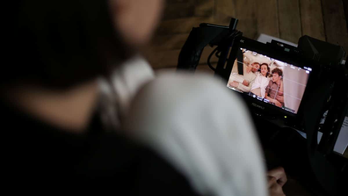 A film crew member reviews footage on a monitor, capturing a behind-the-scenes look at the creative process.