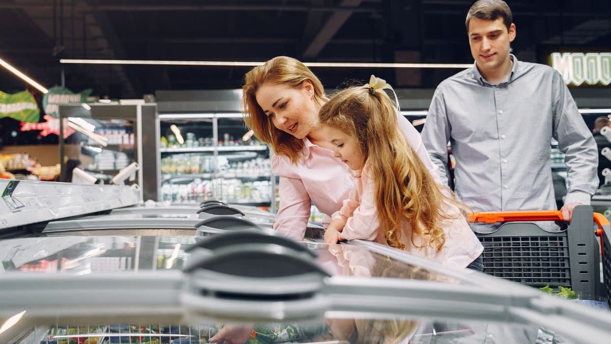 A happy family shopping in the supermarket's freezer section, emphasizing togetherness and love.