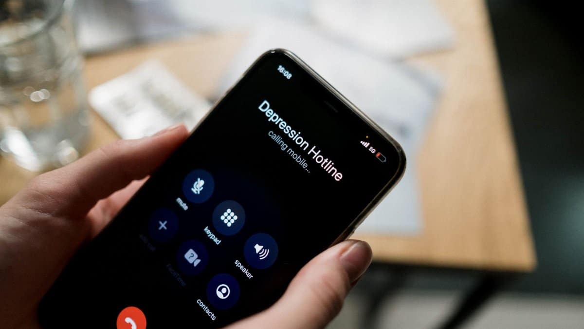 Close-up of a person holding a smartphone, calling a depression hotline.