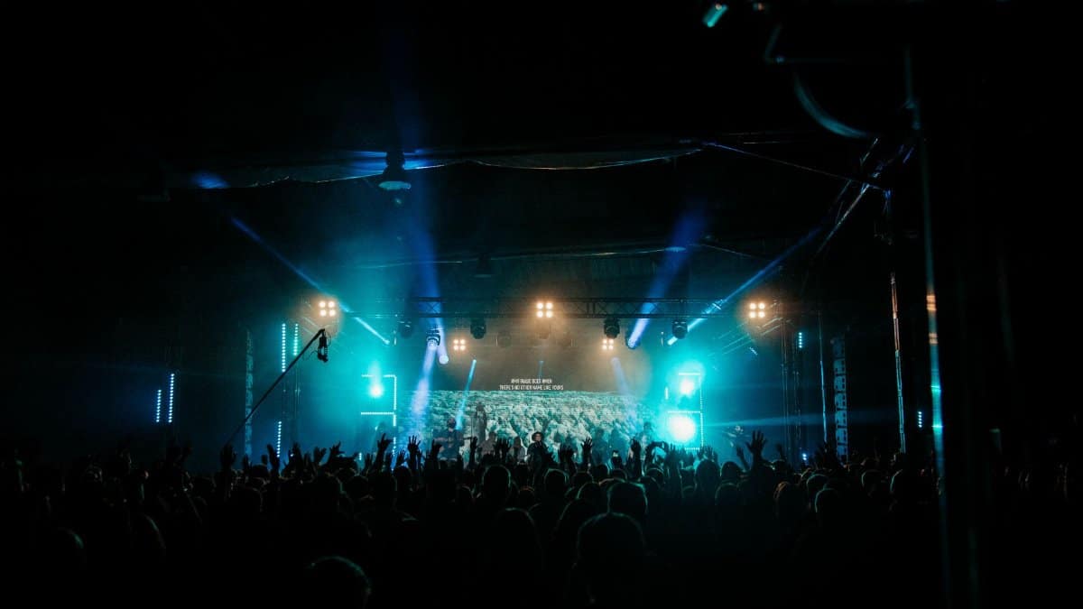 Energetic crowd enjoying live music at a night concert with dazzling stage lights.